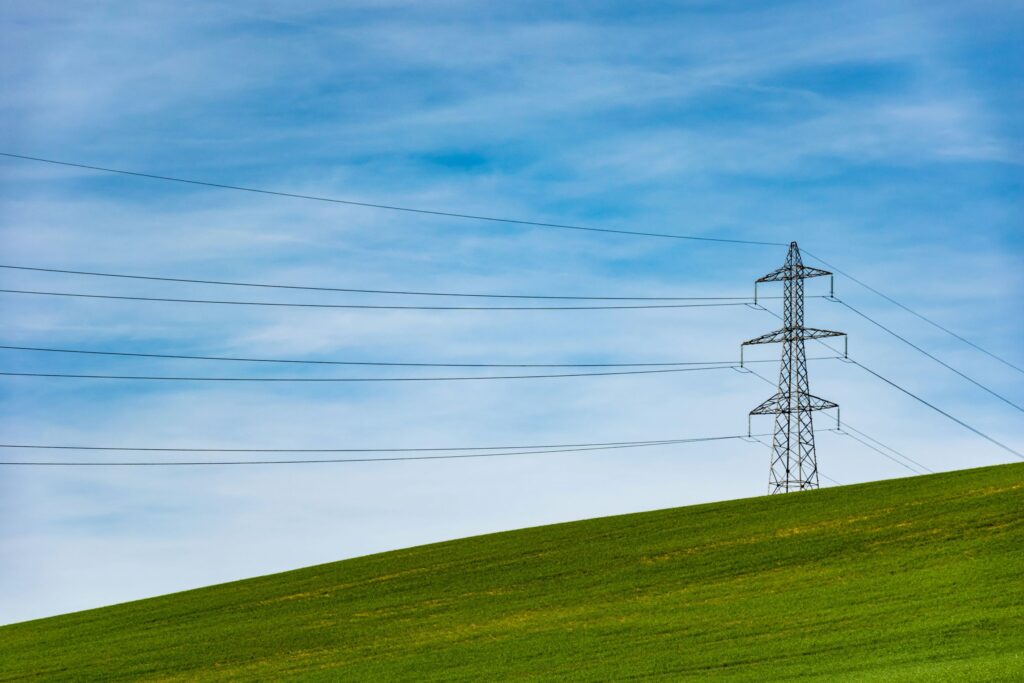 A power line and pylon on a green hill